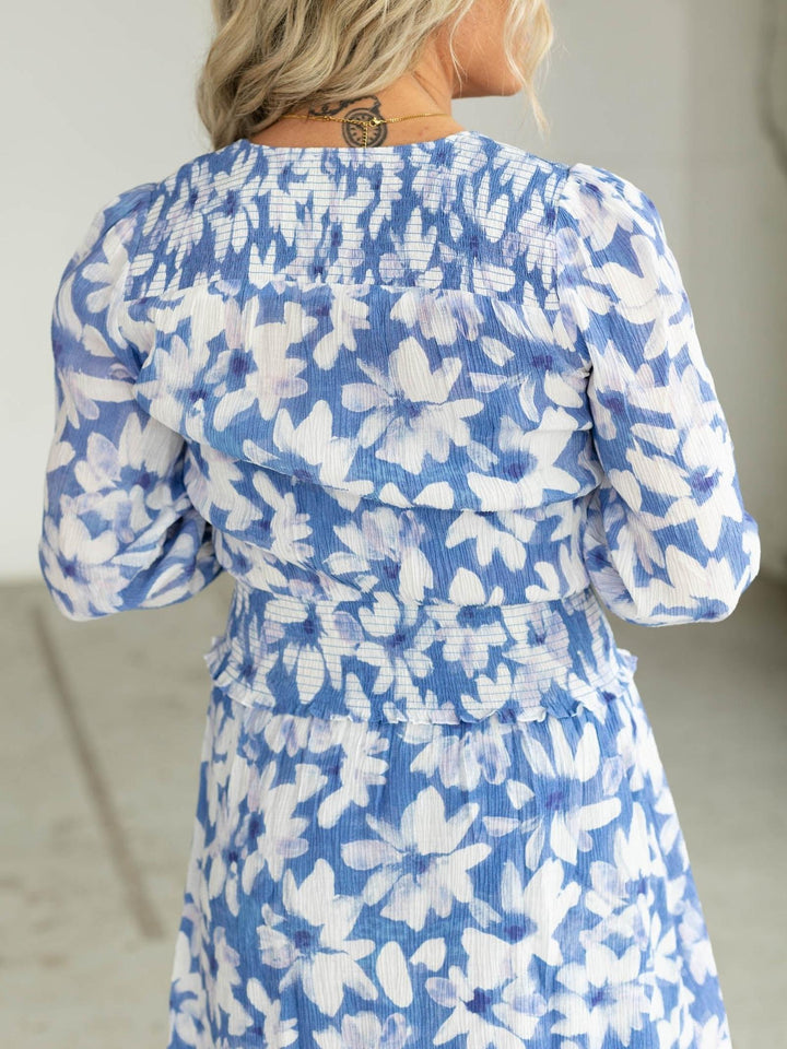 Woman wearing a blue and white floral dress with a neutral background
