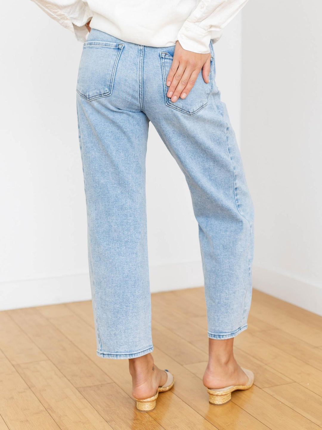 Light blue jeans worn by a person on a wooden floor with a white background