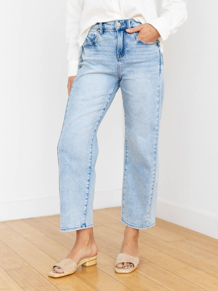 Light blue jeans worn by a person on a wooden floor with a white background