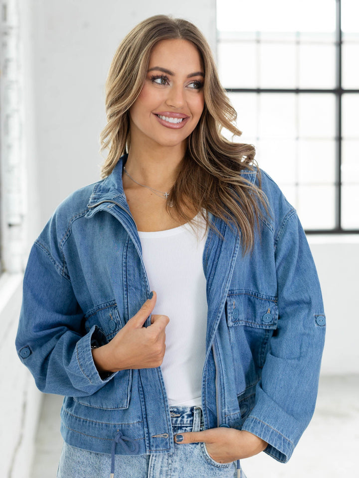 Woman wearing a blue denim jacket and white top indoors