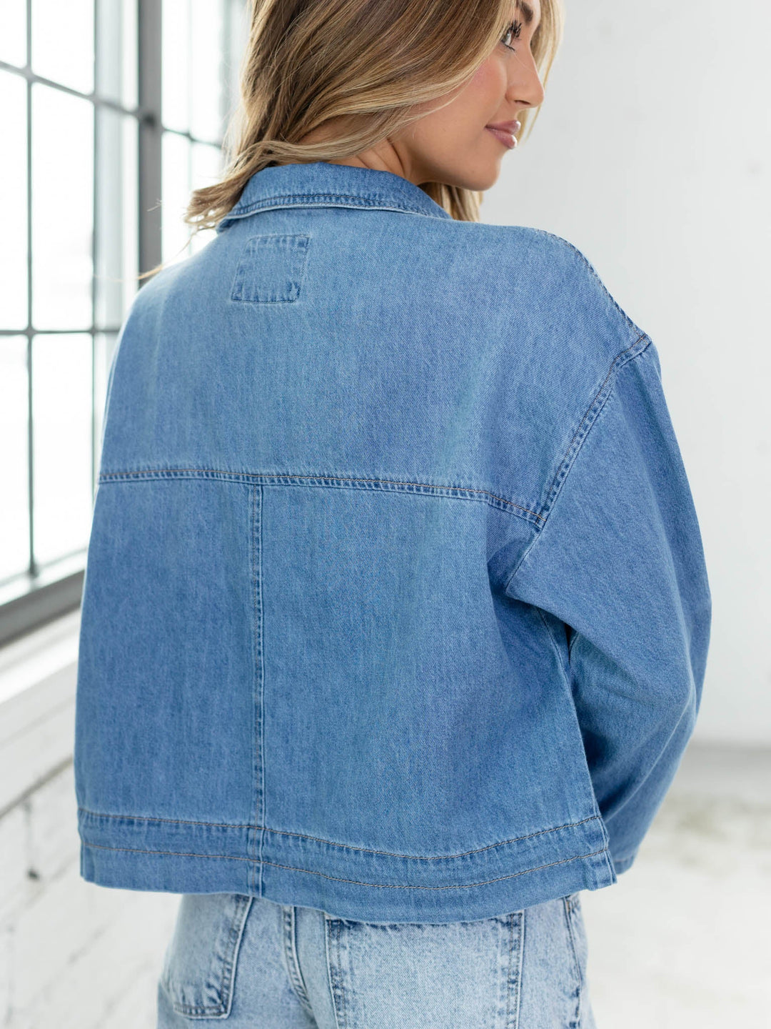 Person wearing a blue denim jacket in an indoor setting