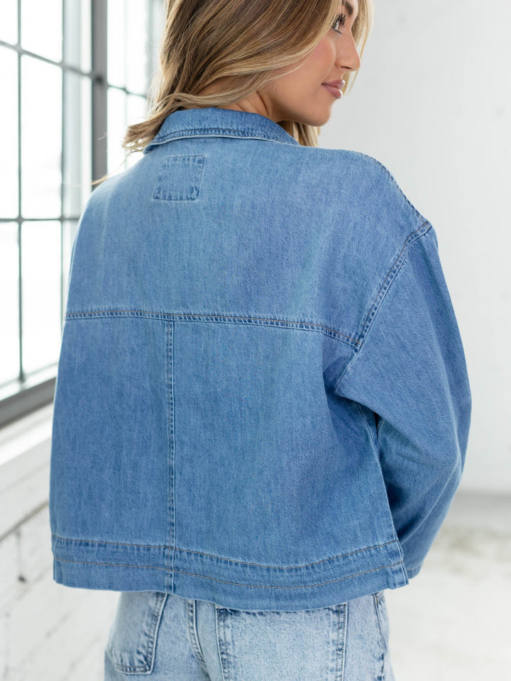 Person wearing a blue denim jacket in an indoor setting