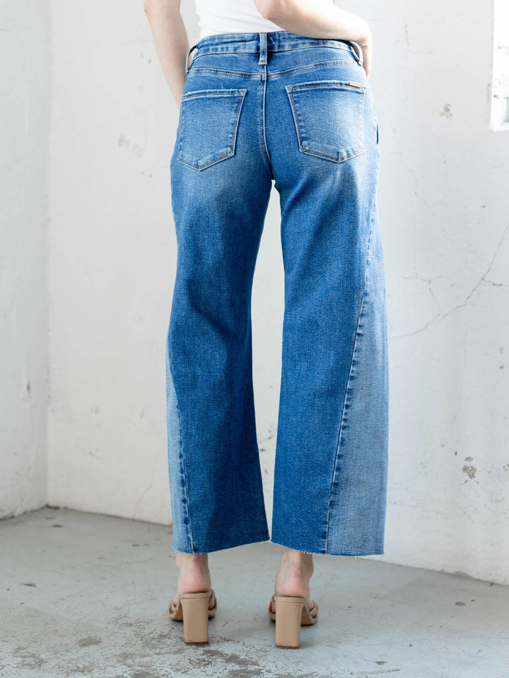 Person wearing blue wide-leg jeans against a white wall.