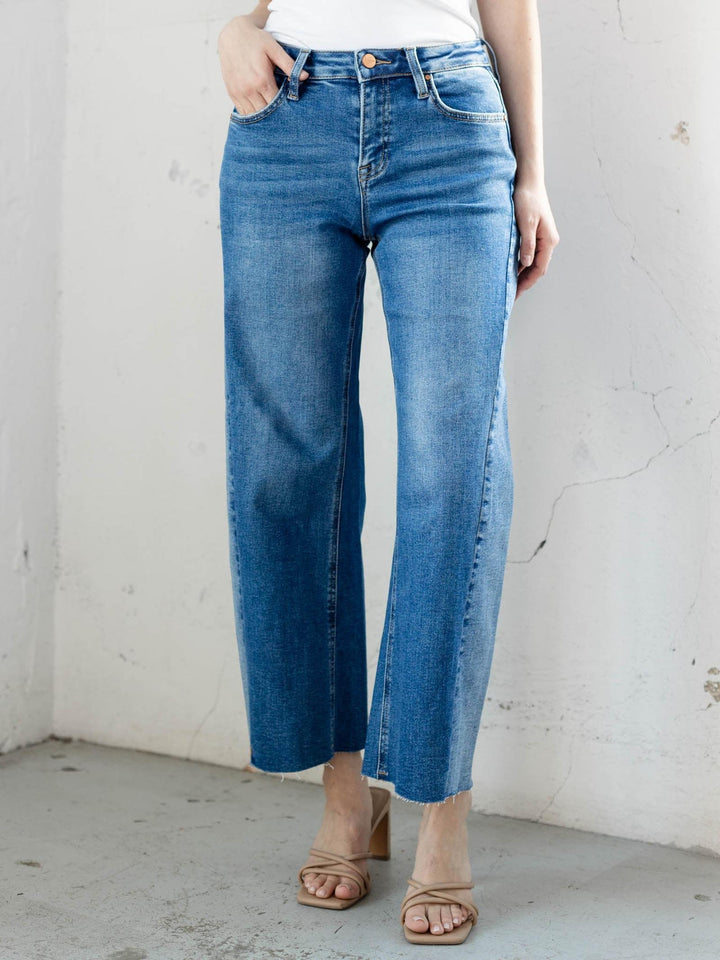 Person wearing blue jeans against a plain white wall