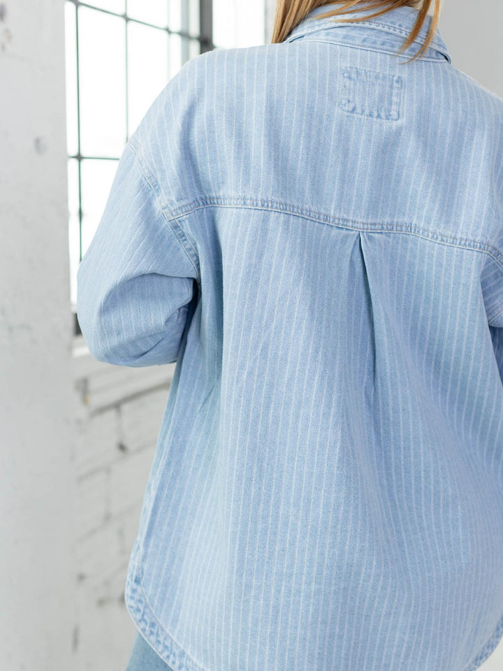 Light blue denim shirt worn by a person with a blurred background