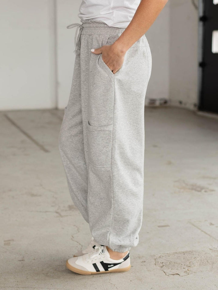 Person wearing gray sweatpants and white sneakers in a minimal indoor setting