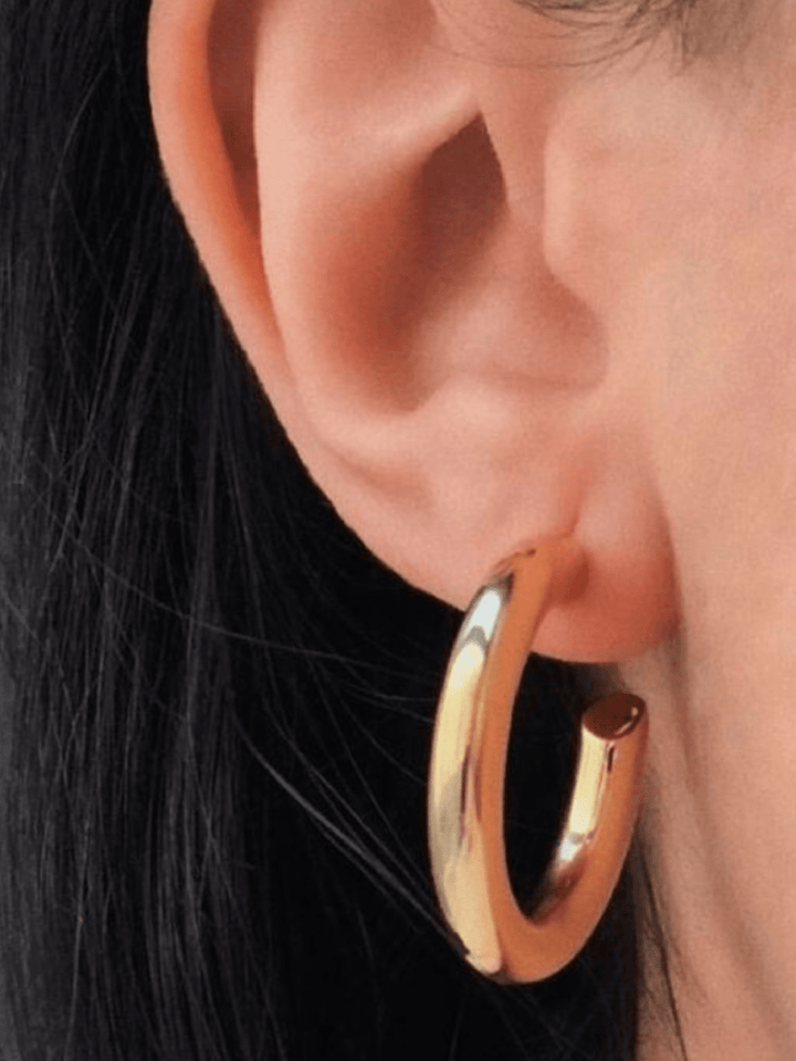 Gold hoop earring worn by a person with dark hair.