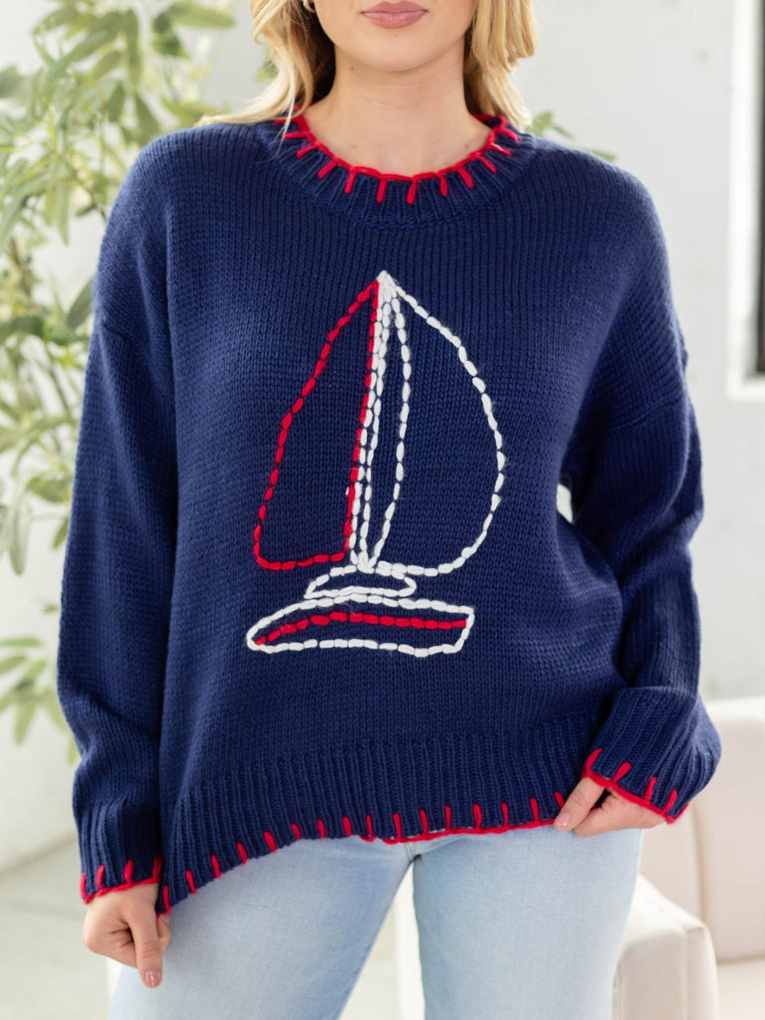 Navy blue sweater with sailboat design worn by a person indoors.