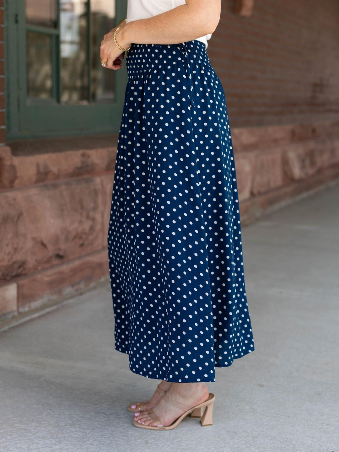 Person wearing a navy blue skirt with white polka dots outdoors.