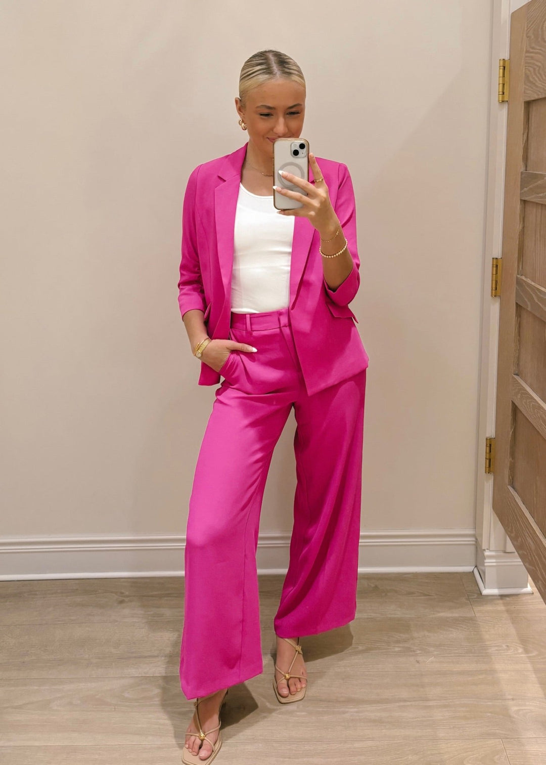 Person wearing a bright pink suit taking a mirror selfie.
