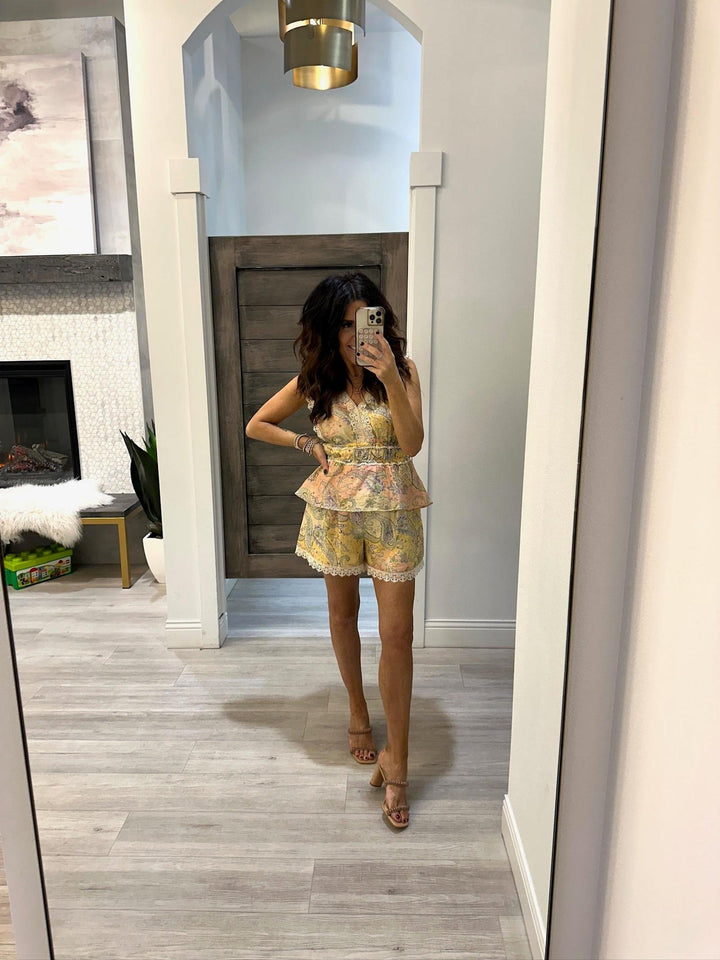 Woman taking a mirror selfie wearing a floral dress in a room with a fireplace and decor.