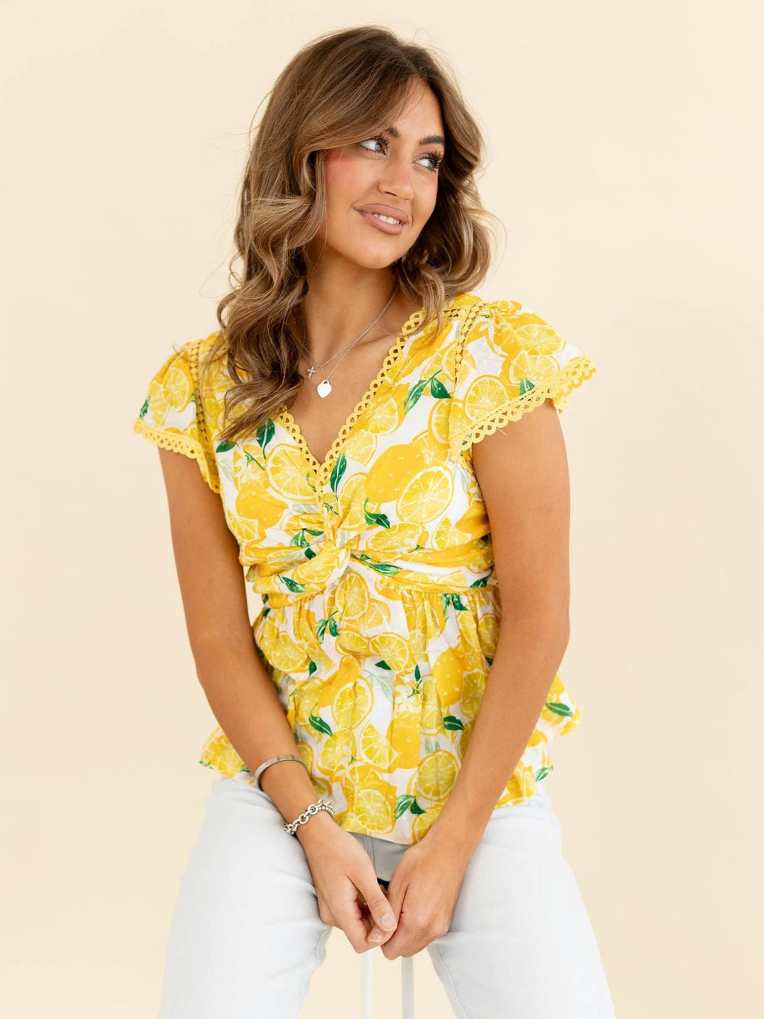 Woman wearing a yellow floral top against a beige background