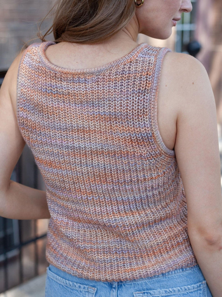 A woman shown from the back wearing a sleeveless, ribbed knit top with horizontal stripes in muted peach, beige, and gray tones, paired with light blue jeans.