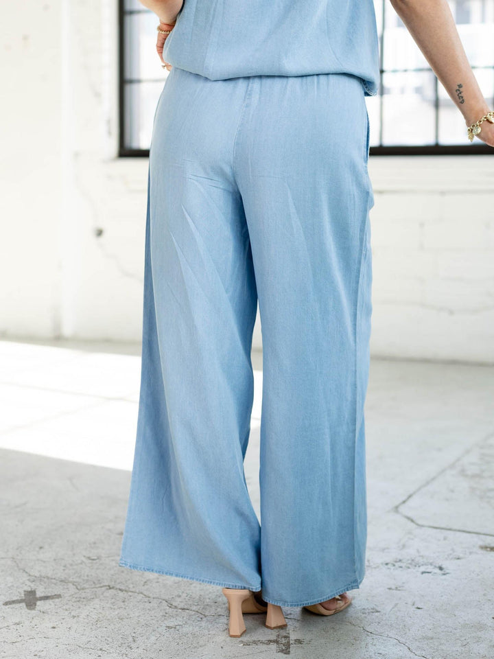 Person wearing a light blue outfit with wide-leg pants in an urban setting.
