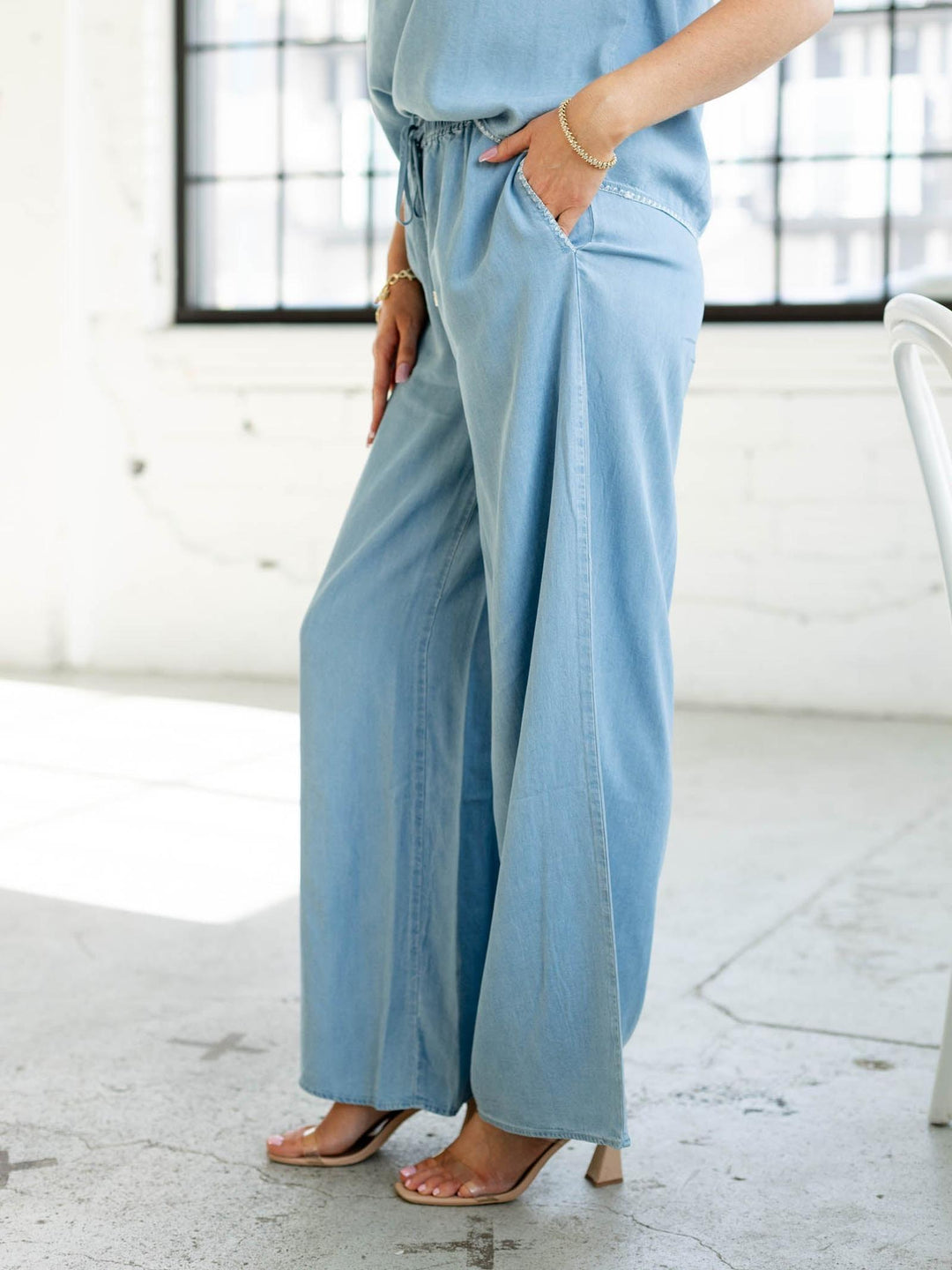 Person wearing light blue pants in a bright room with large windows.