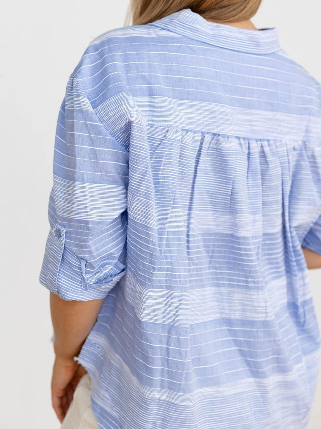 Blue and white striped shirt worn by a person on a plain background