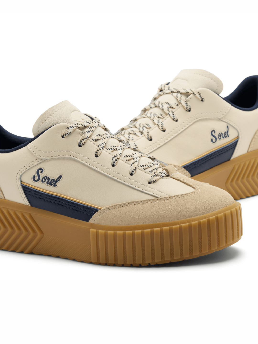 A pair of Sorel platform sneakers in cream suede and canvas, featuring navy blue side stripes with the Sorel logo, cream laces, and chunky tan gum rubber soles.