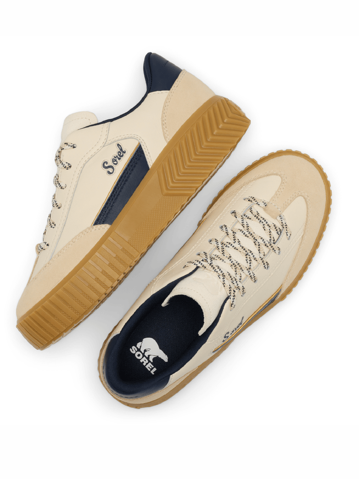 A pair of low-top sneakers shown from top-down and side angles on a white background. The shoes feature cream-colored panels, navy blue accents on the heel, tongue, and inner lining, and tan rubber soles.