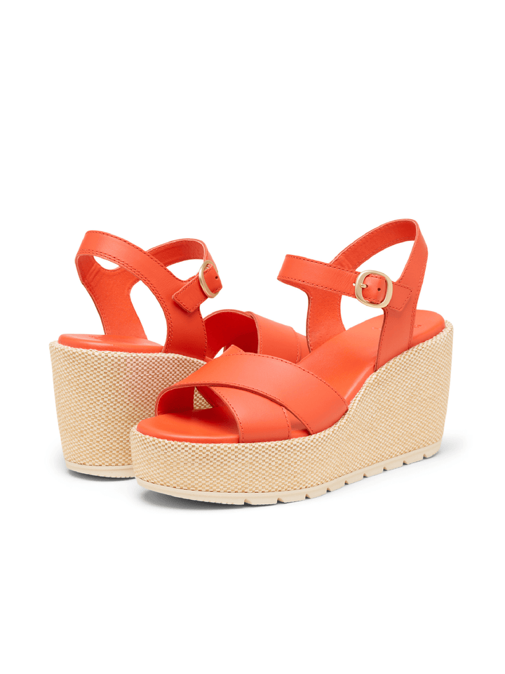 Orange wedge sandals with beige soles on a white background