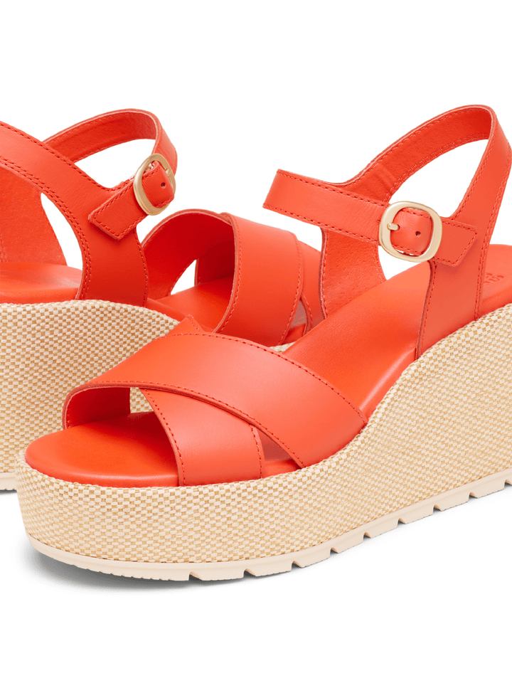 Orange wedge sandals with woven sole on a white background