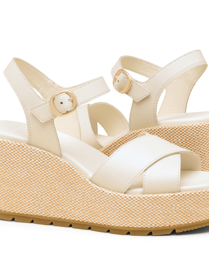Beige wedge sandal with a textured sole on a white background