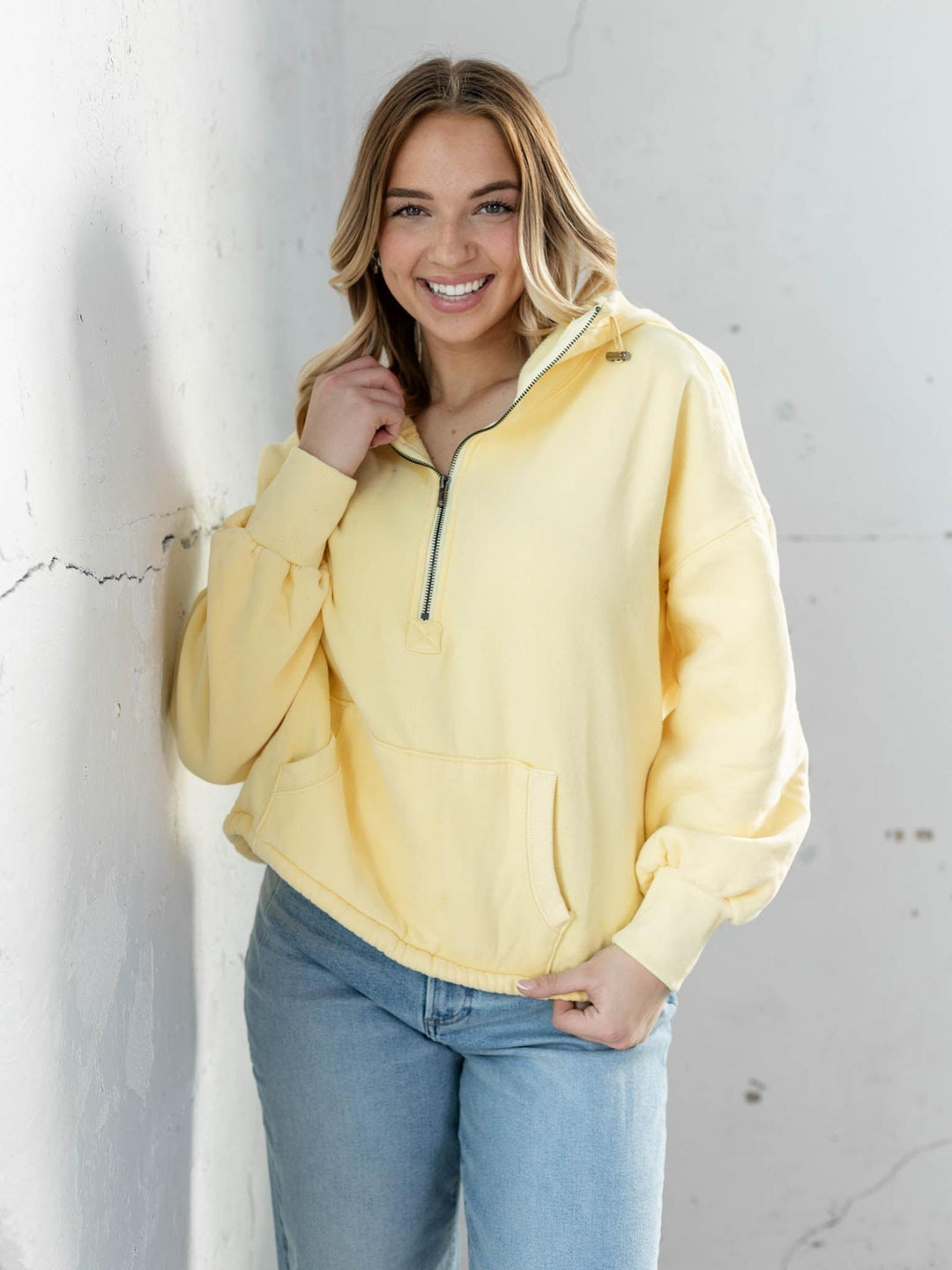 Woman wearing a yellow pullover against a light gray wall