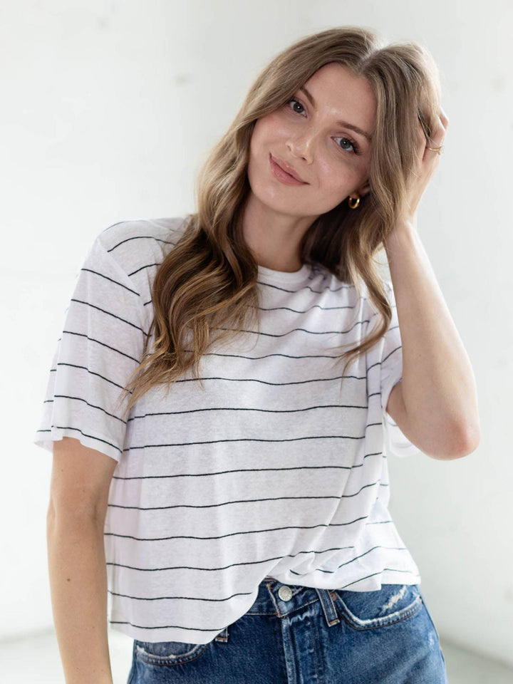 Woman in a white and black stripe cotton-linen blend top with a crew neckline, paired with denim.