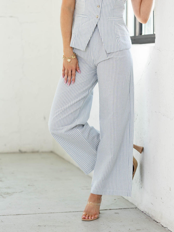 Person wearing a striped suit with wide-leg pants against a white background