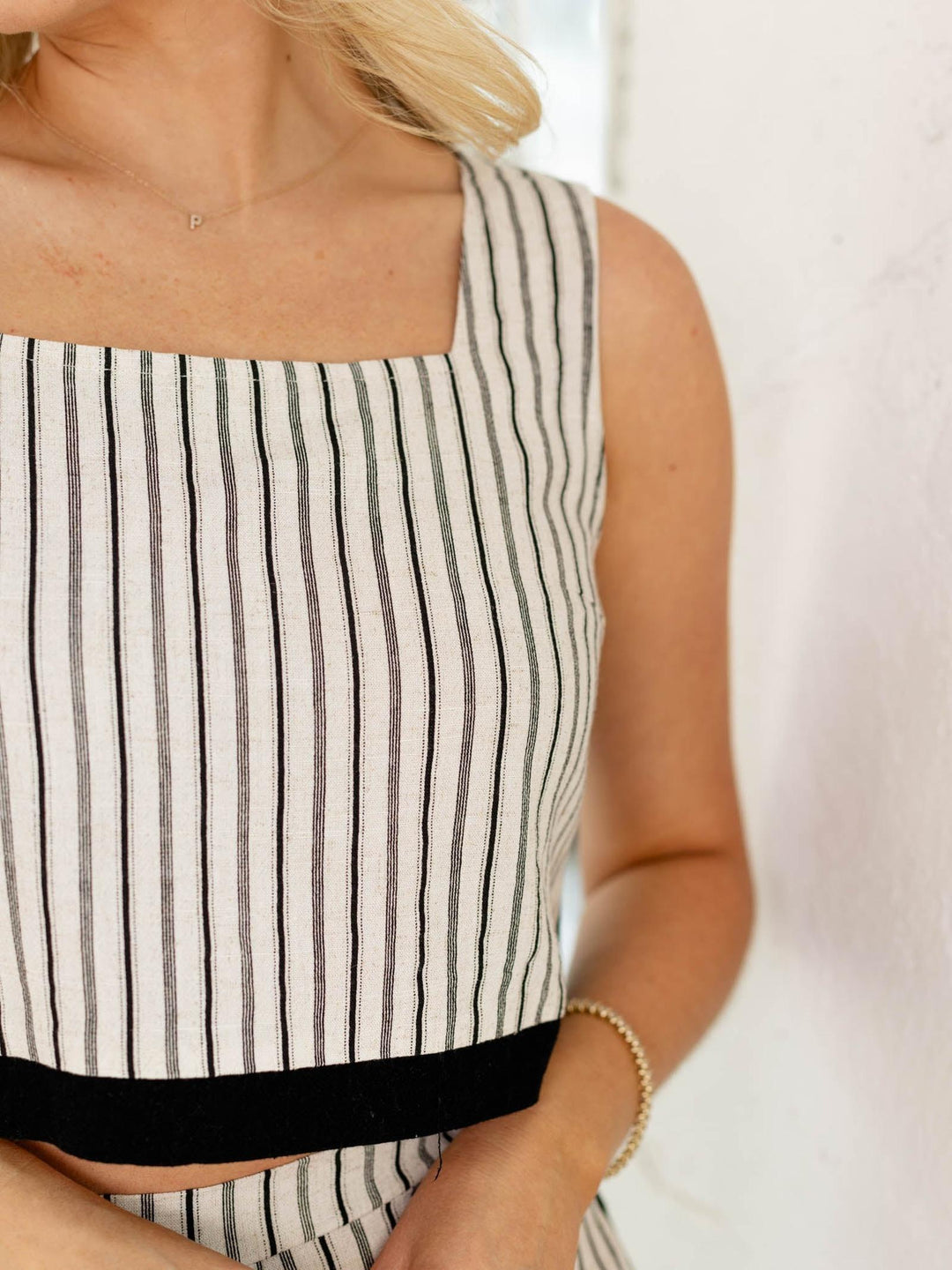 Person wearing a black and white striped sleeveless top with a blurred background