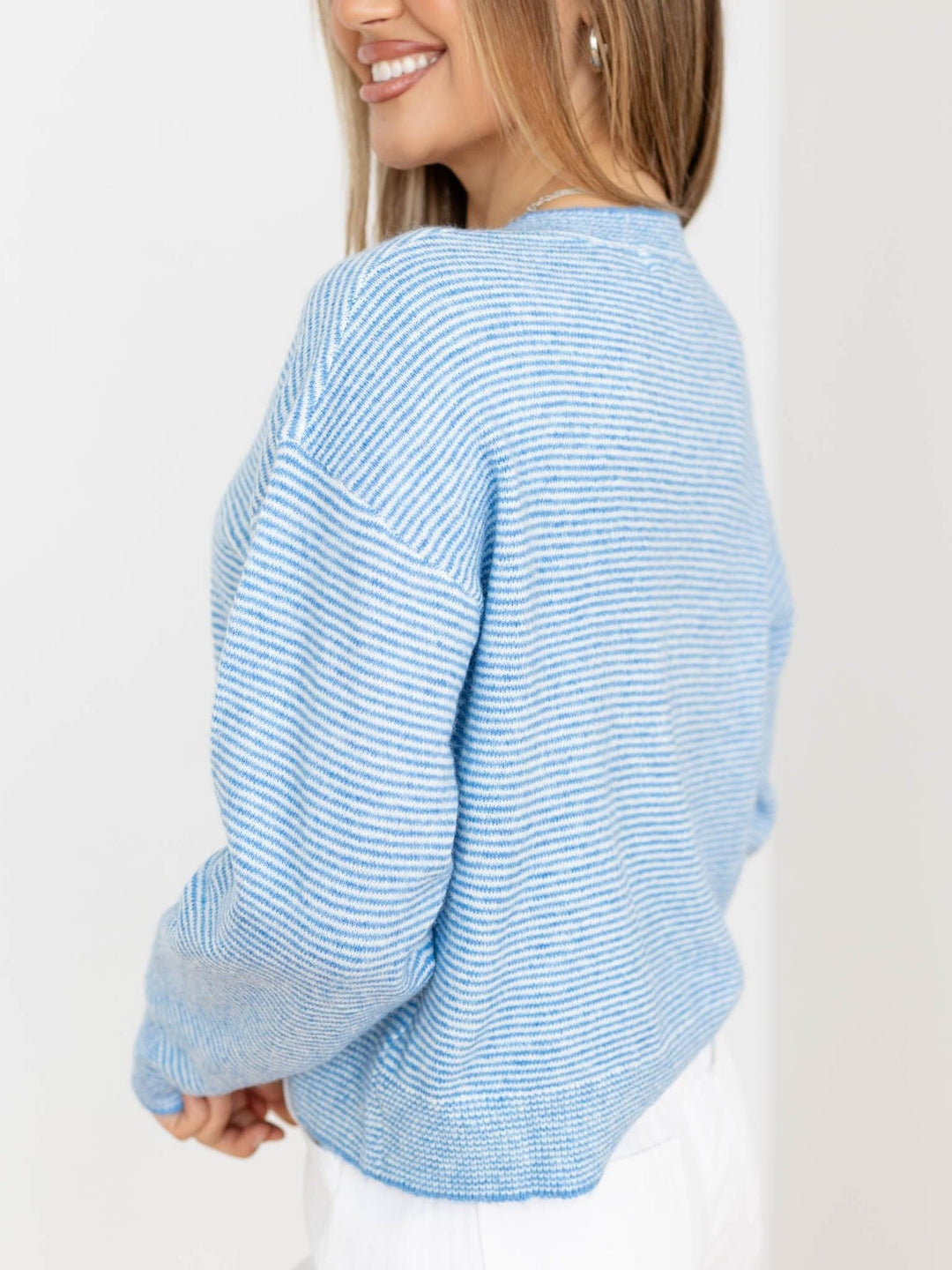 Woman wearing a light blue striped sweater on a white background