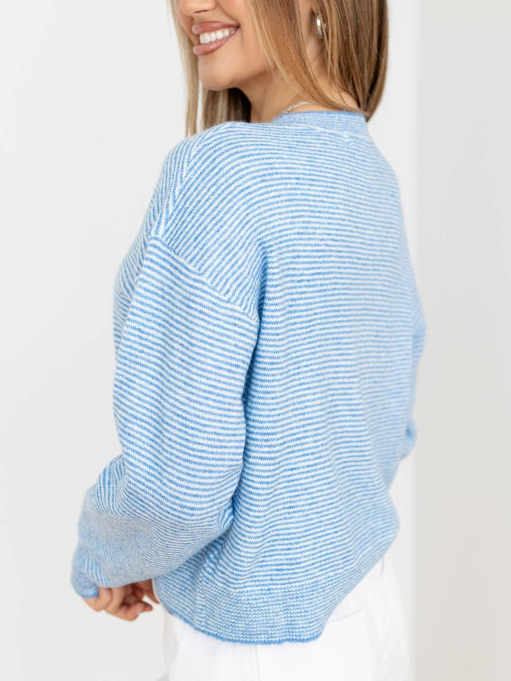 Woman wearing a light blue striped sweater on a white background