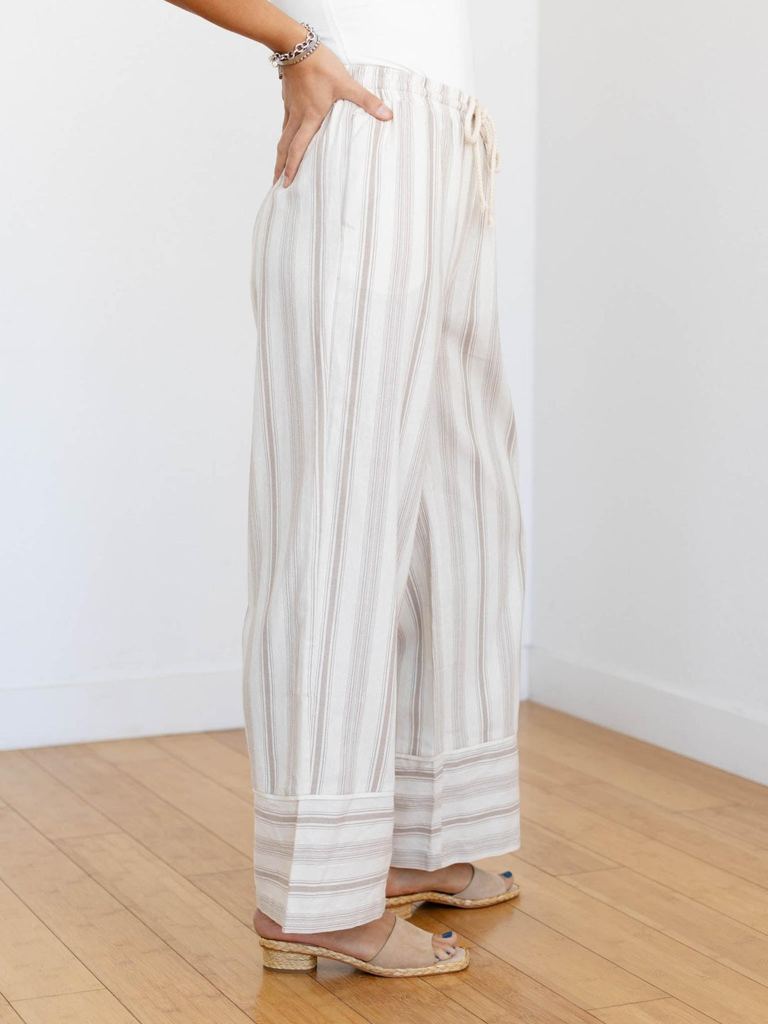 Person wearing white and beige striped pants on a wooden floor.