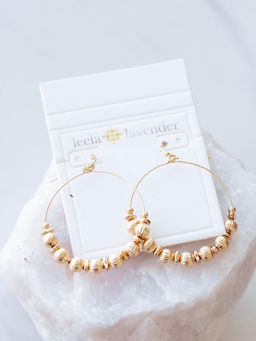 Gold hoop earrings on a white card with &