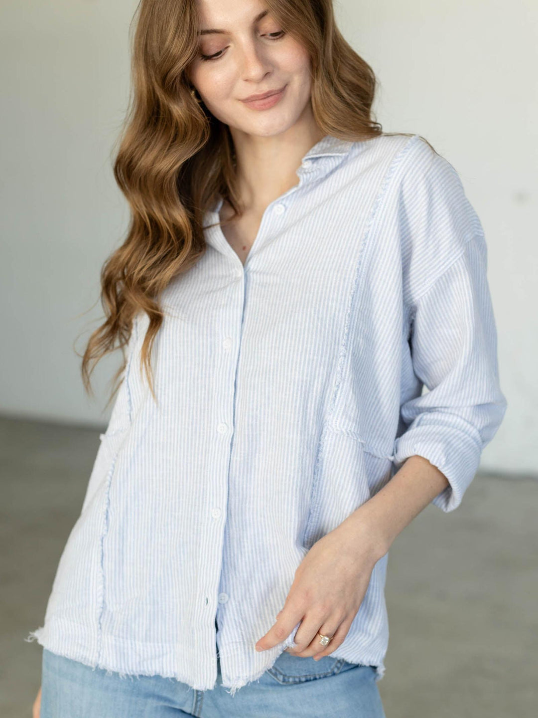 Woman wearing a light blue striped shirt against a neutral background
