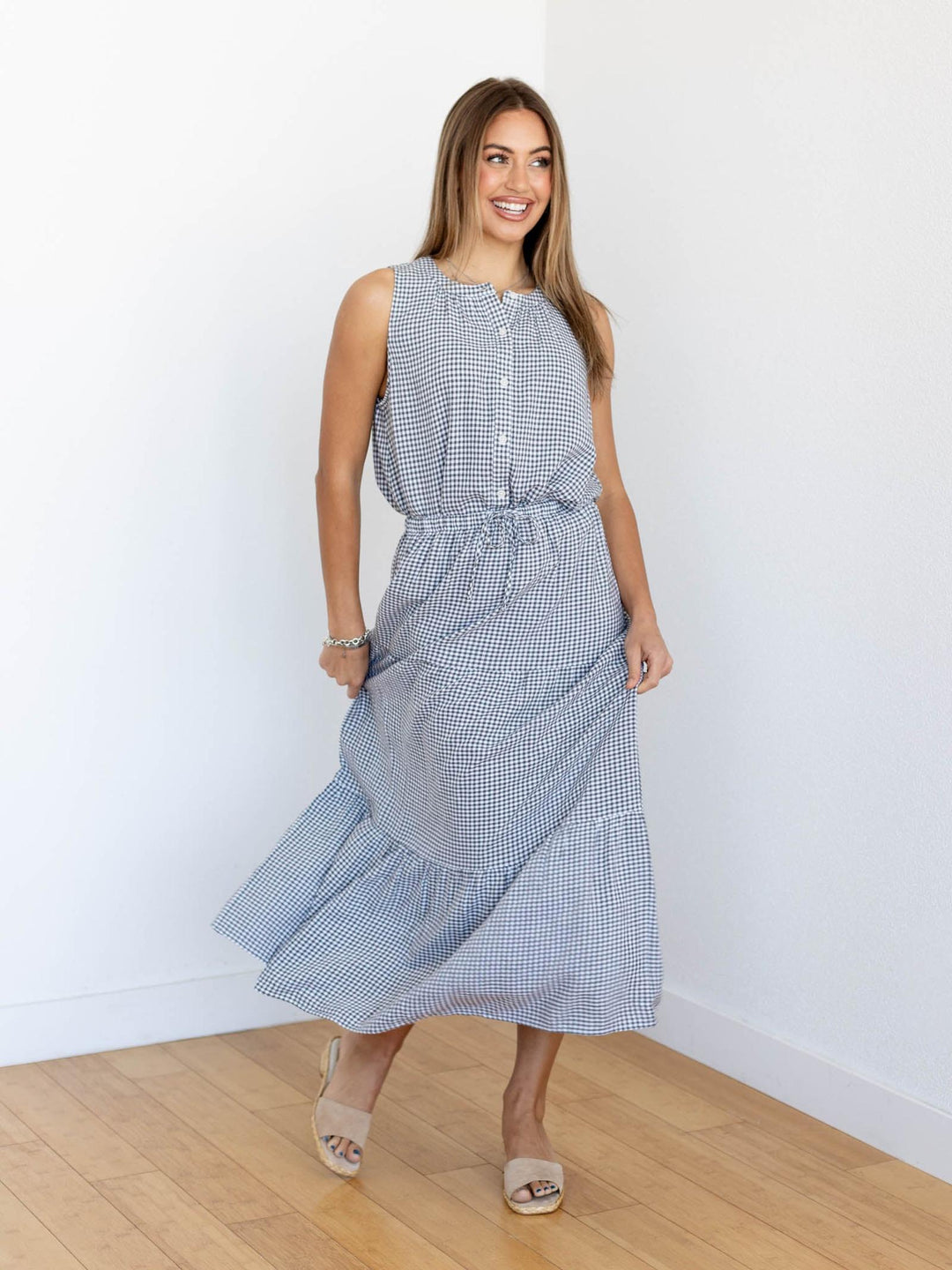 Woman wearing a blue checkered dress against a white wall