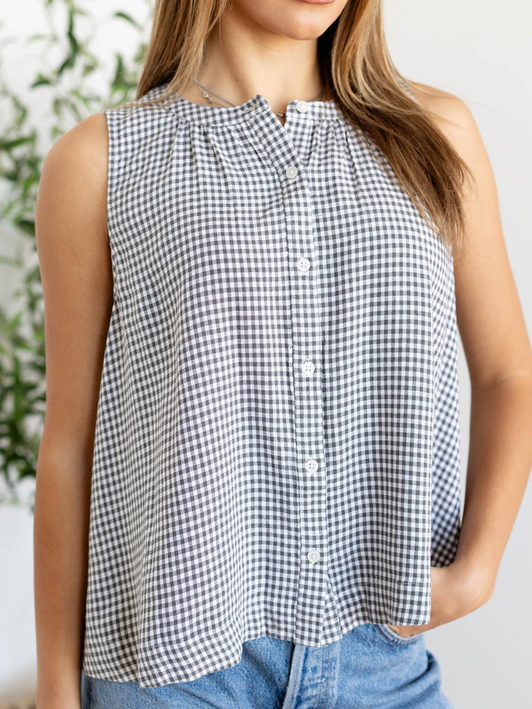 Person wearing a black and white checkered sleeveless top with a blurred background