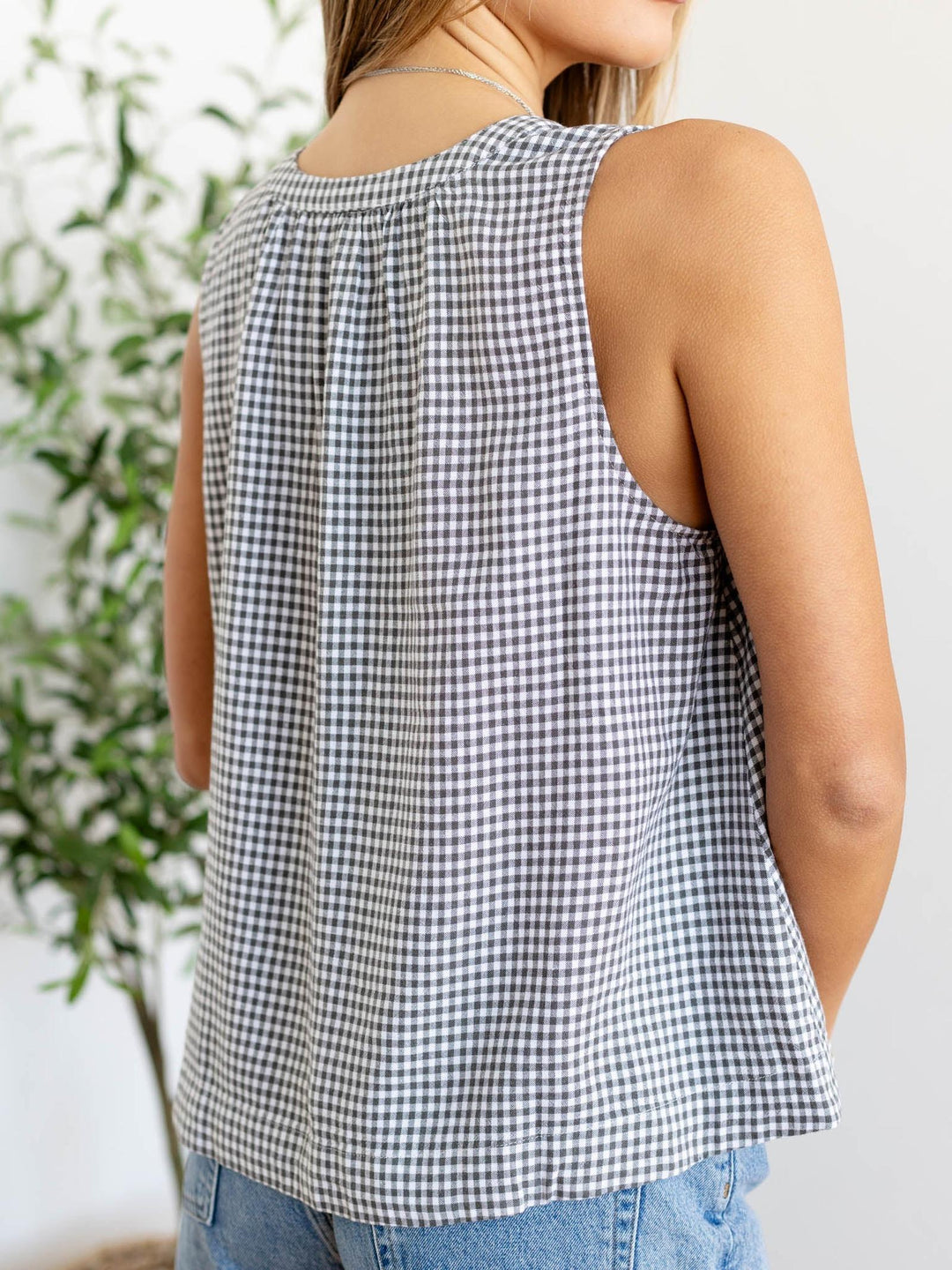 Person wearing a black and white checkered sleeveless top with a blurred background