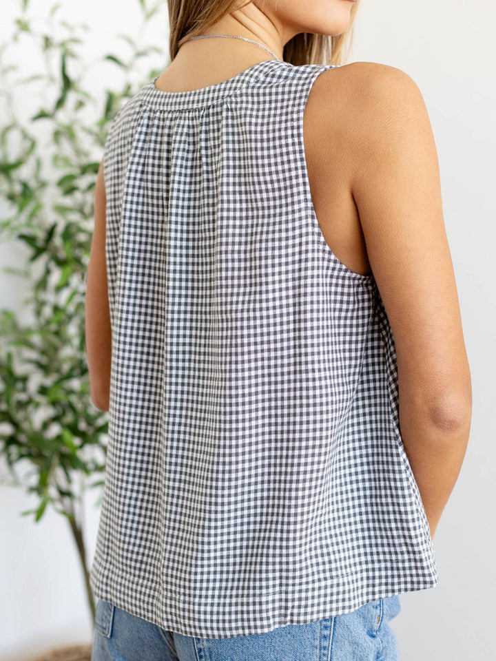 Person wearing a black and white checkered sleeveless top with a blurred background