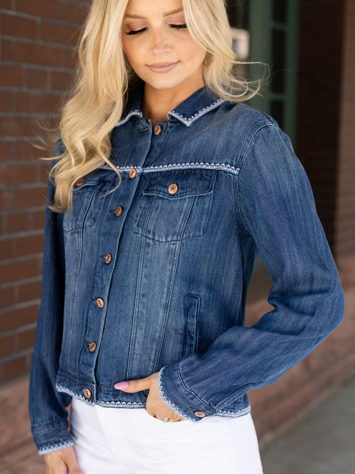 Woman wearing a blue denim jacket with white trim against a blurred background