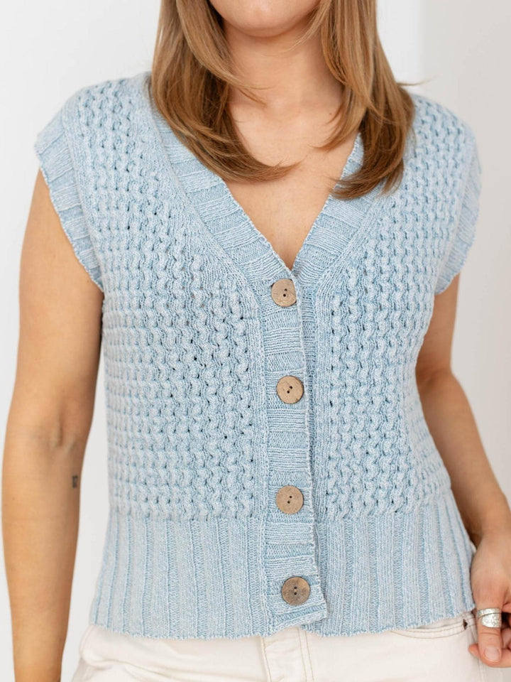 Light blue knitted vest with buttons worn by a person on a white background