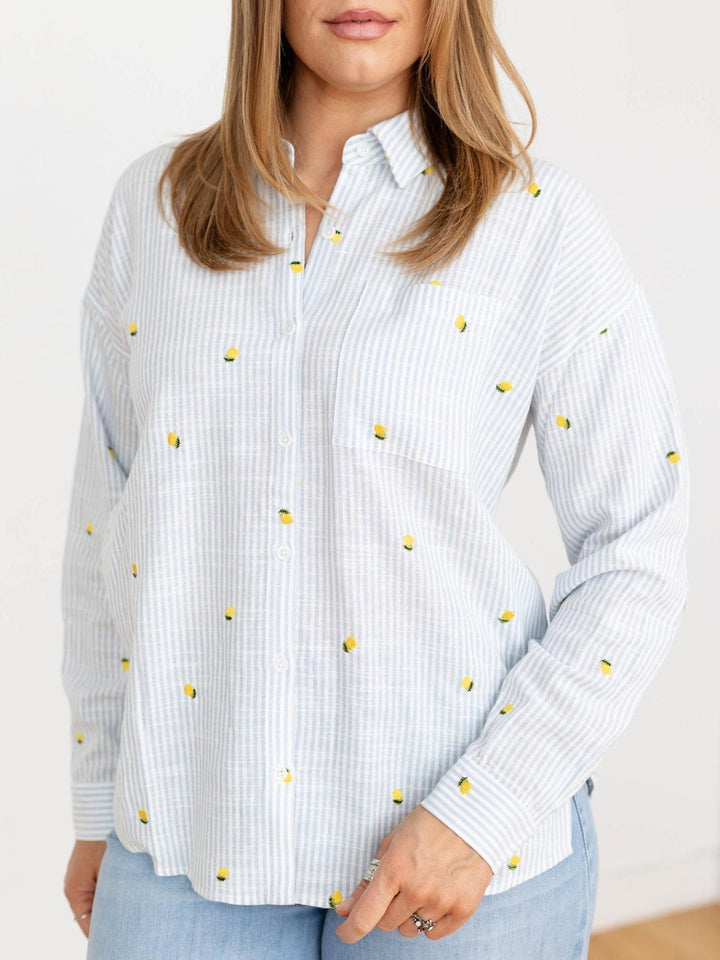 Woman wearing a white shirt with yellow polka dots on a plain background