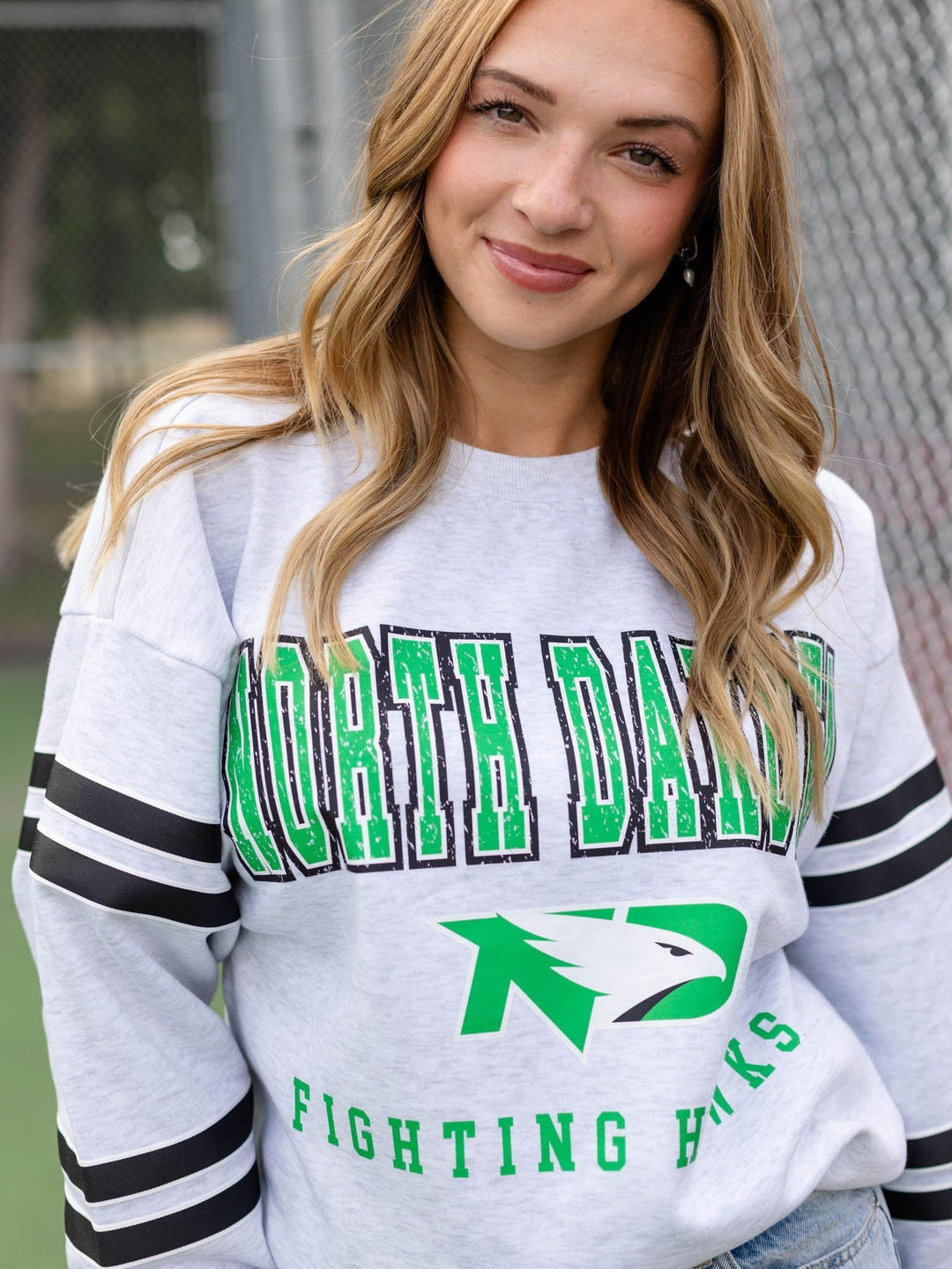 A woman wearing a light gray heather crewneck sweatshirt with &