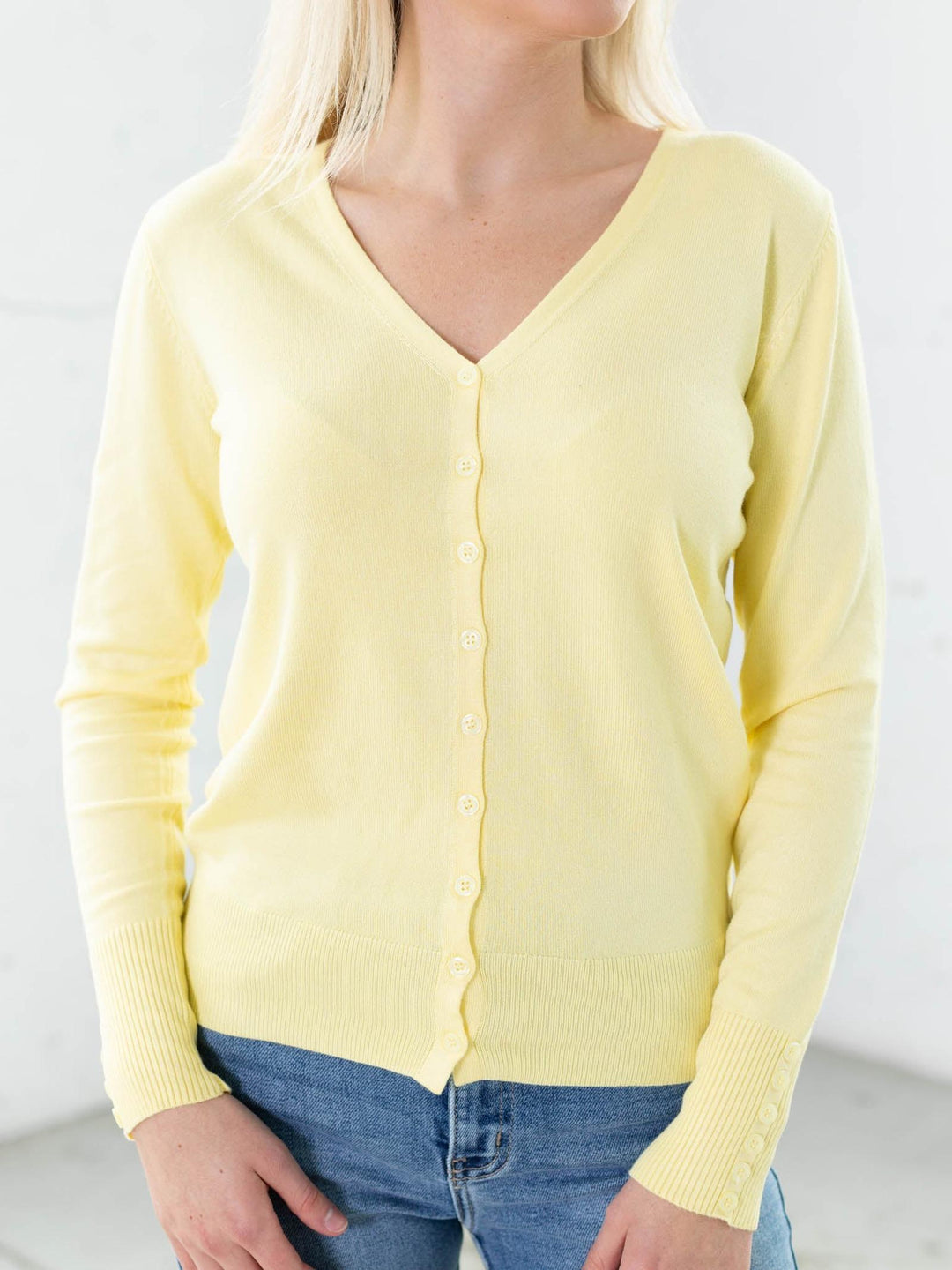Yellow cardigan worn by a person on a plain background