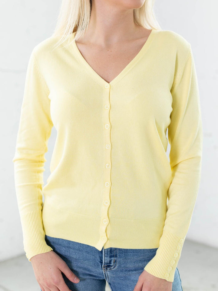 Yellow cardigan worn by a person on a plain background