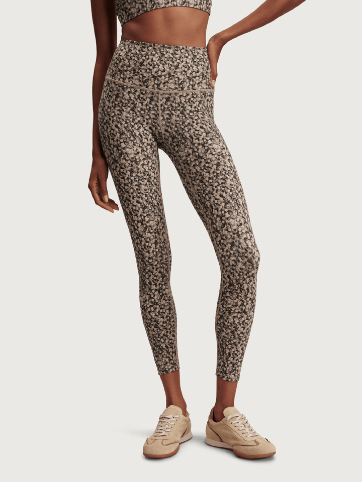 Person wearing patterned leggings and sneakers on a white background
