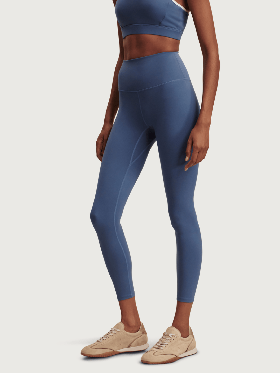 Person wearing blue athletic leggings and sports bra on a white background