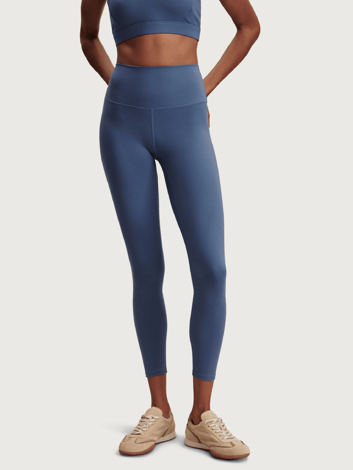 Person wearing blue leggings and a matching top on a white background