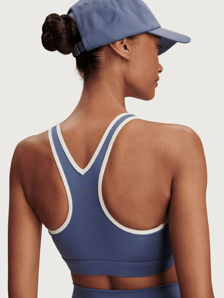 Person wearing a blue sports bra and cap on a plain background
