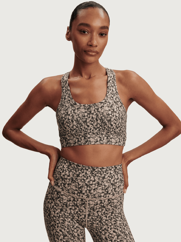 Woman wearing a patterned sports bra and leggings on a plain background