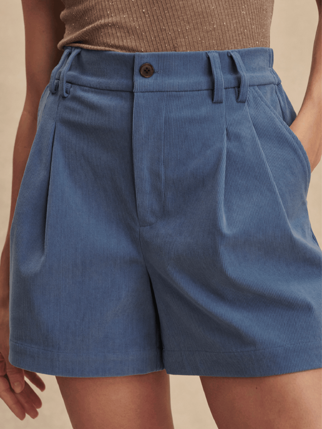 Blue shorts worn by a person on a beige background